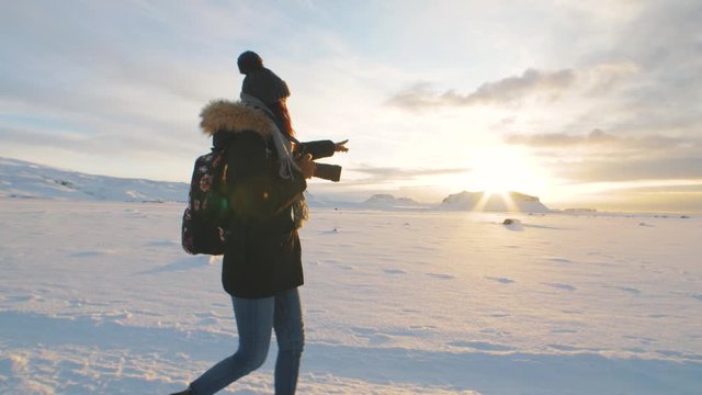Yong beautiful woman traveler walking on snow desert in Iceland. Slow motion shot at sunset or sunrise. Around Solheimasandur dc3 Plane crash area 