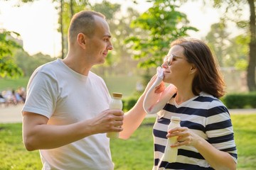 Happy mature couple in park, resting drinking yogurt, dairy after sports exercises