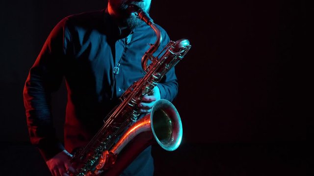 saxophonist plays the saxophone, black background, isolated