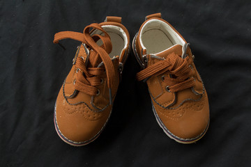 pair of orange shoes for kid on black background