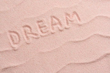 DREAM lettering on sand with wave. Minimal exotic vacation and travel concept, Flat lay top view copy space