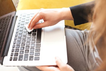 woman wiping laptop keyboard with wet disinfectant wipes due to corona virus infection risk
