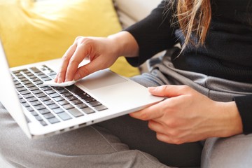 woman wiping laptop keyboard with wet disinfectant wipes due to corona virus infection risk