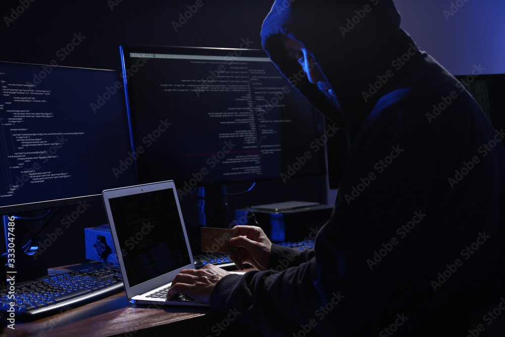 Poster hacker with computers and credit card in dark room. cyber crime