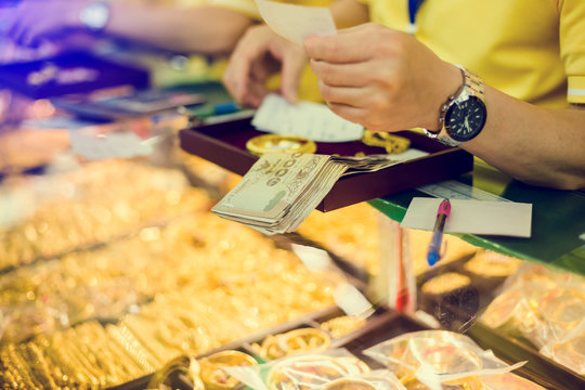 selective focus to staff are counting banknote, customers are buying gold jewelry in the gold shop.