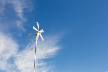 Close up wide angle view of a spinning wind turbine charging batteries in an off the grid electricity installation on a farm in the Karoo in the Western Cape of South Africa