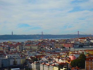 Fototapeta na wymiar Skyline of Lisbon's red roofs, in the background the bridge on April 25th and Christ the King on a sunny day.