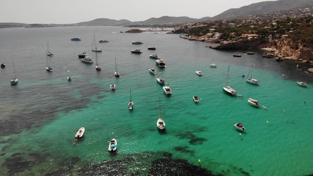 Yachts in turquoise seawater in the cove, summertime. Punta des Bufador in Playa de Illetas beach is beautiful and popular tourist destination in Majorca. Aerial drone 4K cinematic footage