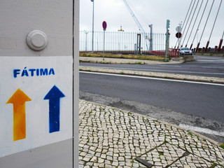 Indications for the Portuguese route to Fatima against the backdrop of the bridge rods in Lisbon.