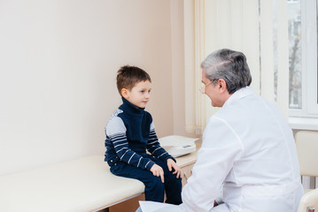 Fototapeta premium A young boy is listened to and treated by an experienced doctor in a modern clinic. A virus, and an epidemic