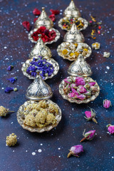 Assortment of dry tea in golden vintage mini plates.Tea types background:hibiscus,chamomile,mixed black tea,dry roses,butterfly pea tea