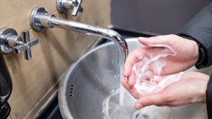 A man washing his hands with soap in a public place. Virus prevention. Close up Hygiene concept. Measures to stop coronavirus pandemic.