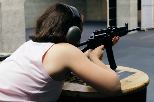 Girl in headphones shoots a carbine in shooting range