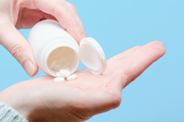 Close up woman pours the pills out of the bottle. Medicine and health care.