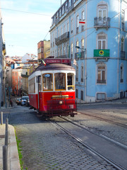 Red tram in Lisbon illuminated by a ray of sunshine in the background the city downhill
