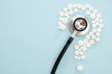 Concept medical of exam, diagnosis and treatment, stethoscope on blue background with mix pills