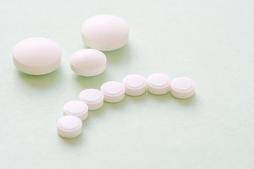 Sad patient face made from white round pills on green