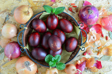 Easter eggs in wicker basket and onion, top view
