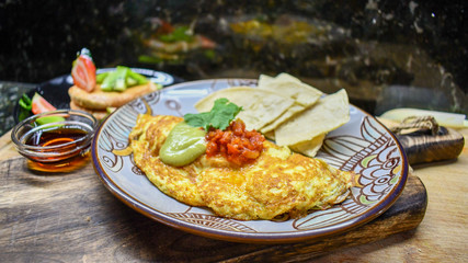 Egg omelette with red salsa, avocado salsa and corn tortilla chips.