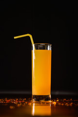 Orange juice with yellow straw isolated on black background