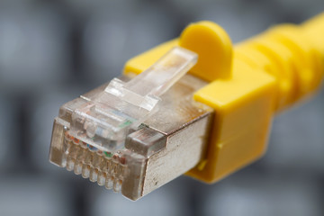 yellow lan cable connector on a dark blurred keyboard