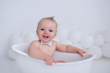 Little boy takes a bath. Water treatments with yellow ducks.