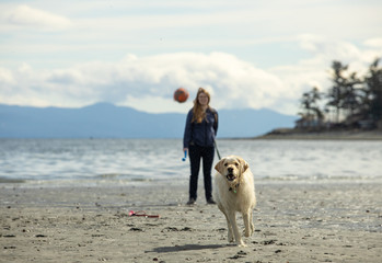 Woman with her dog on the beach on Vancouver Island Canada as he chases a ball