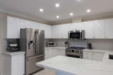 High gloss Kitchen with new white quartz countertops with gray veining, subway tile backsplash and stainless steel appliances.