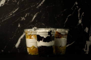 vanilla and chocolate cake in a cup mixed with white icing on a marble background