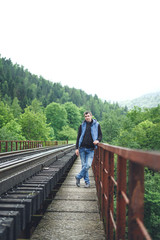 Young man in jeans on a railway track. Man in the mountains