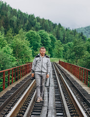 Handsome young man with a camera on a background of railway tracks.