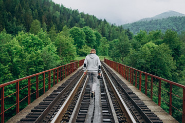 Fototapeta premium Handsome young man with a camera on a background of railway tracks.
