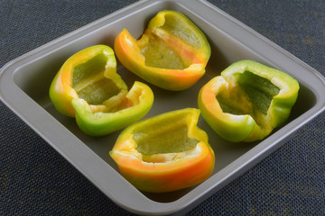 Fresh raw bell pepper halves with seeds removed in nonstick baking pan ready for filling