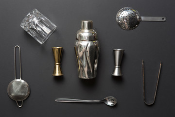 Flat lay composition with bartender iron tools, such as cocktail shaker, jigger, mixing glass,...