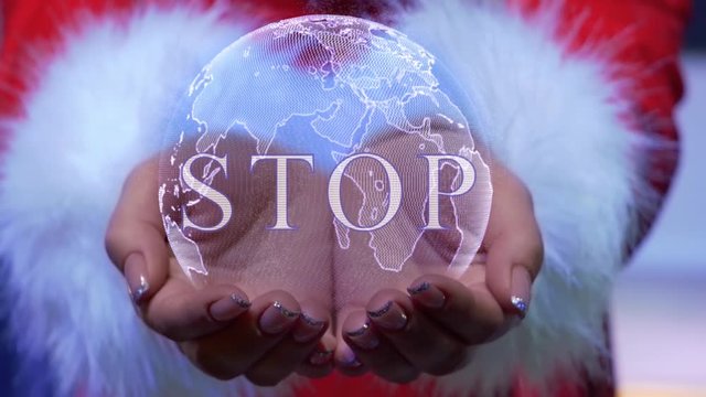 Female hands holding a conceptual hologram of planet Earth with text Stop. Woman in red clothes with faux white fur with future holographic technology