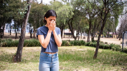 mujer joven estornudando en parque