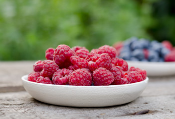 Still life with a blueberries and raspberries on an old wooden table, at the garden. Rural natural food style.