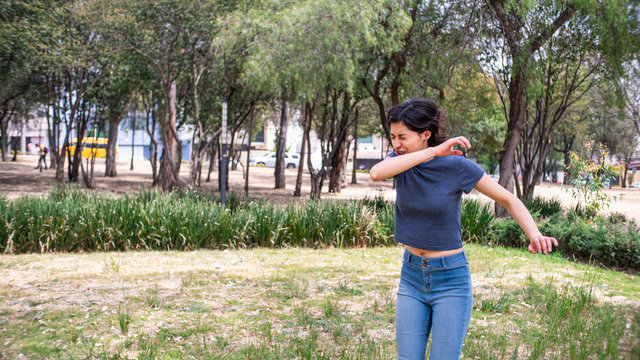 mujer joven estornudando en codo