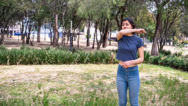 mujer joven estornudando en codo