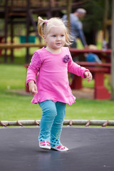 Close up image of a little blond toddler girl playing outside