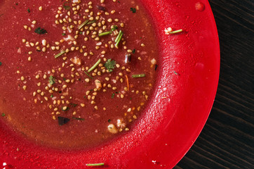 Salad leftovers after meal. Oil, tomato seeds, chopped parsley on a single red plate. Closeup shot