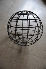 Hollow ball, made of wire. Tiled surface in the background.