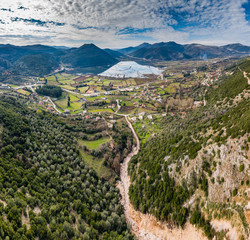 Flight over the flooded valley in Greece. The flooded fields, roads, mountains on background, the inhabited settlement. Reflection of mountains in water