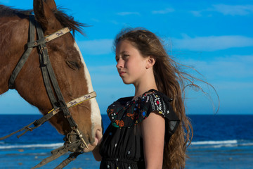 Dziewczynka z koniem na plaży spogląda w dal