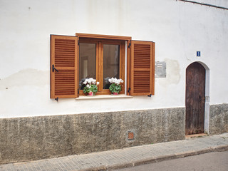 Obraz na płótnie Canvas Brown shutters and flowers on the windowsill.