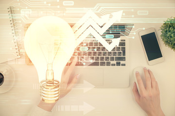 Double exposure of woman hands working on computer and light bulb hologram drawing. Top View. Idea concept.