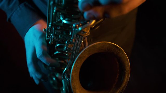 Man's fingers playing on the saxophone beautiful blues melody. Close up. Black background