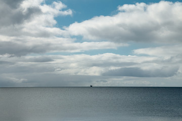 Vast seascape with a lone ship on the horizon. Big sky.