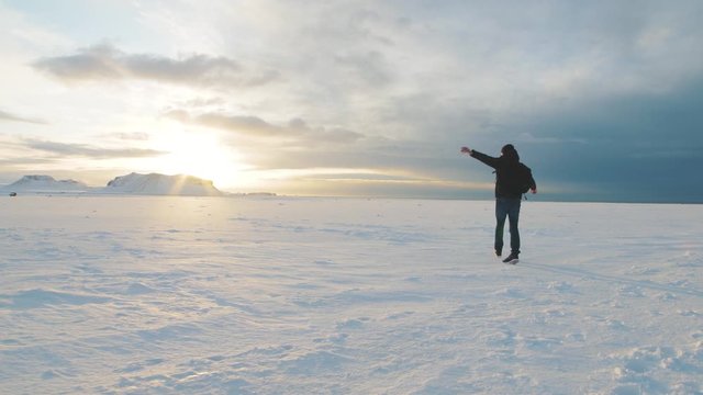 Young man traveler walking on snow desert in Iceland. Slow motion shot at sunset or sunrise. Around Solheimasandur dc3 Plane crash area 