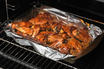 Oven baked chicken wings in the home kitchen. With a golden crispy crust. Close-up